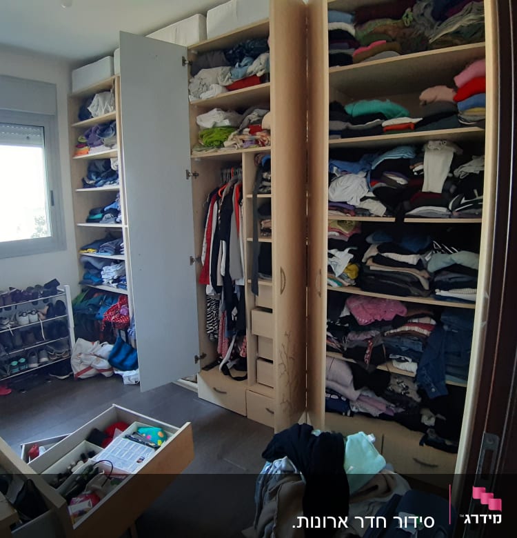 ארון בגדים פתוח עם מדפים מלאים בבגדים מקופלים